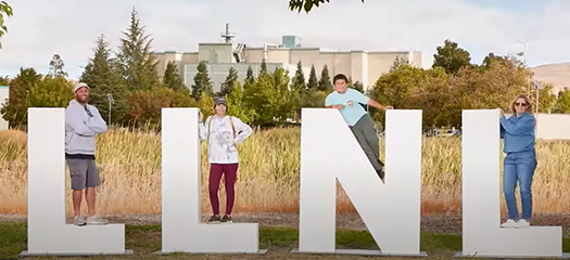 people pose near large LLNL letters