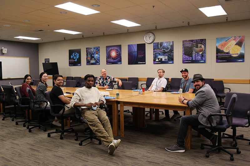 Eight interns and mentors seated at a long table in a conference room