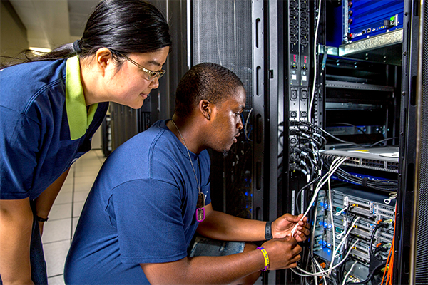 Two students inspect the cables inside an HPC cluster's cabinet