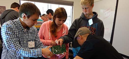 mentors and students inspect a computer motherboard