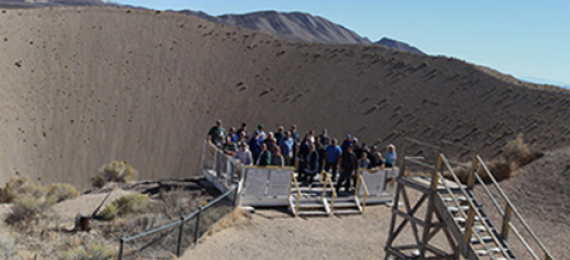 A group poses beside the Sedan Crater during a 2018 tour of NNSS