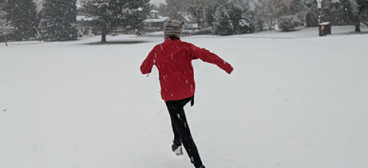 Vanessa running through snow with her back to the camera