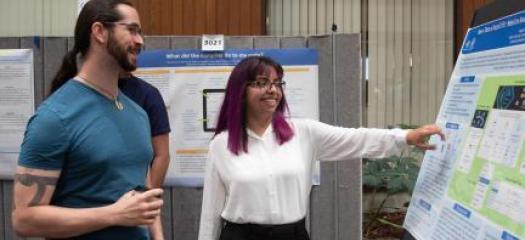 Ian and Angela looking at her poster at the 2019 symposium