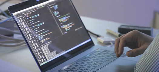 person working at a laptop whose screen is filed with code