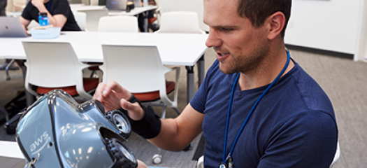 a participant in the hackathon room examines the DeepRacer car