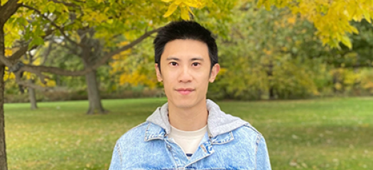 Chen Wang in front of fall-colored trees