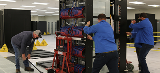 three people install an early access system rack in the machine room