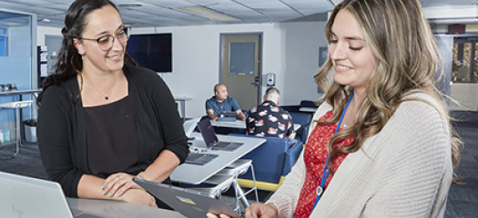 two people confer at a laptop