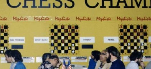  several chess players seated at tables during a competition, in front of competition-related signs on a yellow wall