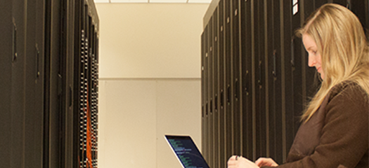 Elsa with a laptop between supercomputer racks