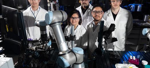 five people in lab coats in a robotics laboratory