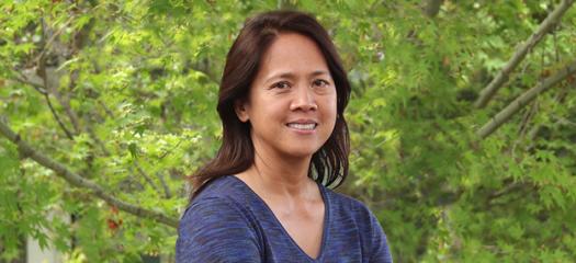 Louella Panaga in front of a leafy tree