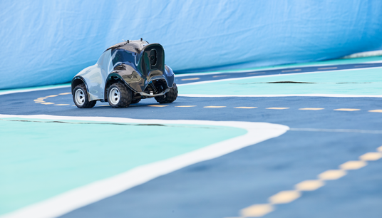 DeepRacer car positioned on the blue track with a dashed yellow center line and white lines marking the outside of the lane