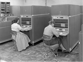 black-and-white photo showing two women working at early computers