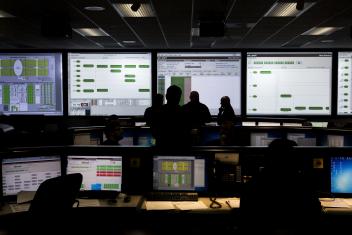 Silhouettes of researchers monitoring many screens of data.