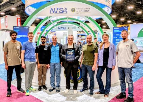 Team stands with award in SC25 DOE booth