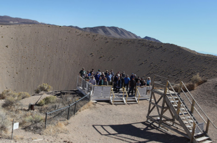 A group poses beside the Sedan Crater during a 2018 tour of NNSS