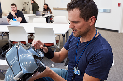 a participant in the hackathon room examines the DeepRacer car
