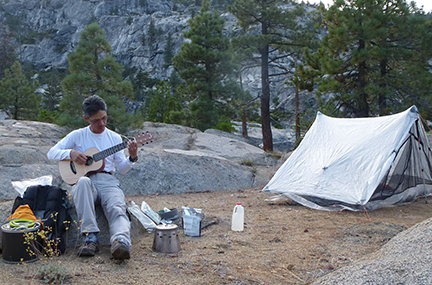 Brian Gunney playing guitar at a campsite