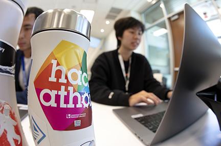 Summer interns work on their hackathon projects. A water bottle with a hackathon sticker on it is in the photo’s foreground.