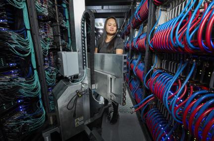 Woman standing between two rows of wires and cabling