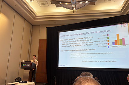 Kathleen presenting at a podium in front of a big screen, which shows a slide titled “User Feedback Requesting More Build Parallelism”