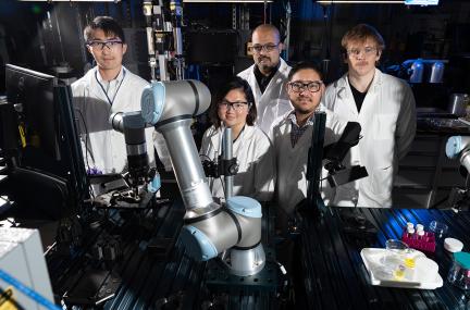 five people in lab coats in a robotics laboratory