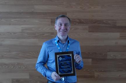 Markus Schordan holds up the plaque honoring the LLNL team’s Test of Time Award for their 2016 paper on Backstroke. 