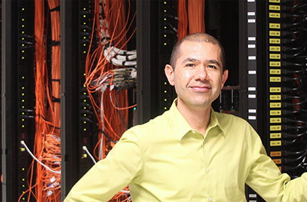 Edgar Leon stands in front of a supercomputer