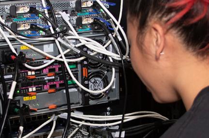 student inspects wires in a supercomputer rack
