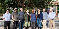 eight people stand side by side in front of the NIF building