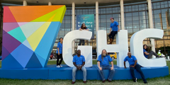 several people posed outside the 2019 conference venue on large GHC letters