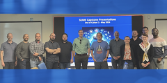 the first cohort of SEAM participants stand as a group in front of a large video screen
