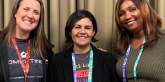 Jamie, Marisol, and AJ pose together in front of a tan curtain