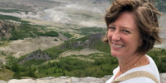 Kathryn on a windy hill overlooking a stone wall and scenic vista