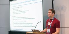 Todd at a lectern next to a presentation screen