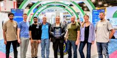 A group of award winners stands in the DOE booth at SC25