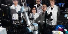 five people in lab coats in a robotics laboratory