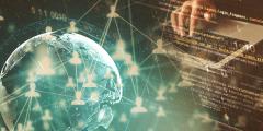 stock image of the Earth overlaid with lines of code and person's hands on a keyboard