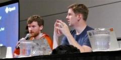 three men at a table speaking on a panel