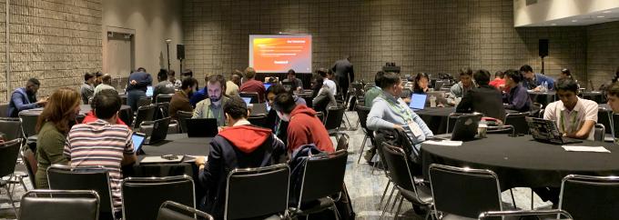 groups of students and mentors collaborate at several round tables in a conference room