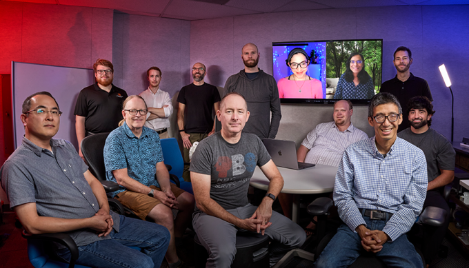 11 people gathered in a room with 2 others in videoconference