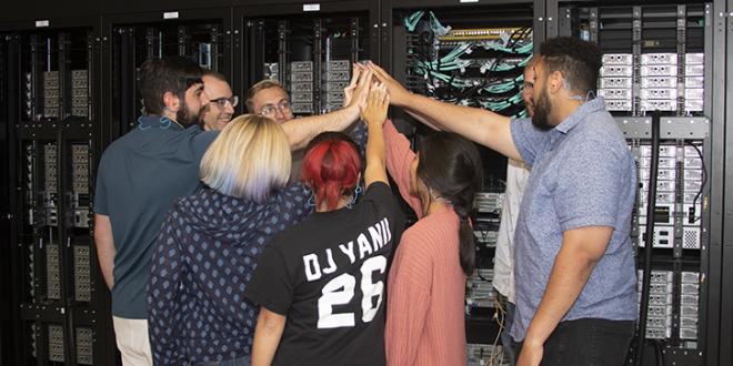 HPC students do a group high-five next to Catalyst
